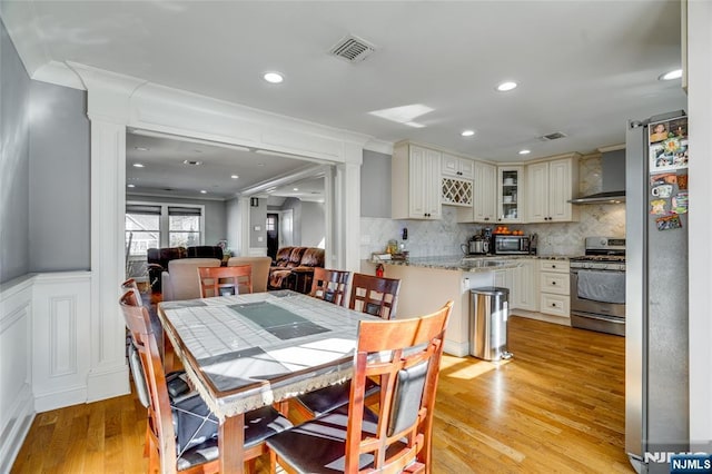 dining space with decorative columns and light wood-type flooring