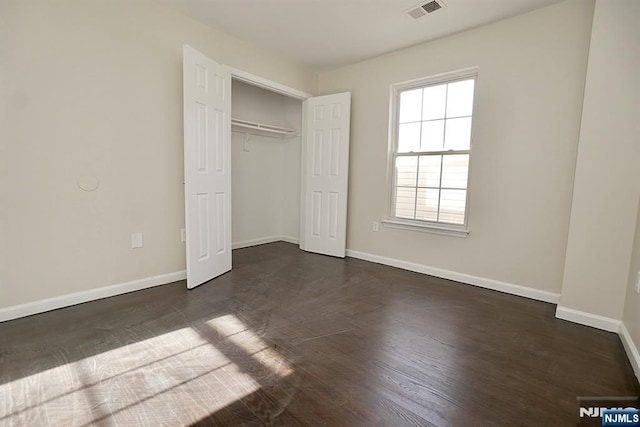 unfurnished bedroom featuring dark hardwood / wood-style flooring and a closet