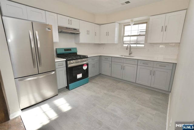 kitchen with stainless steel appliances, gray cabinets, sink, and backsplash