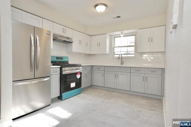 kitchen with sink, gray cabinetry, tasteful backsplash, white cabinetry, and appliances with stainless steel finishes