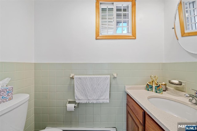 bathroom with vanity, tile walls, and toilet