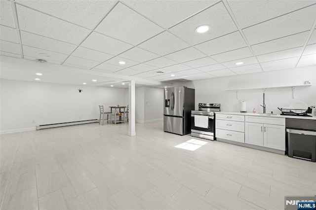 kitchen with stainless steel appliances, a baseboard radiator, a paneled ceiling, and white cabinetry