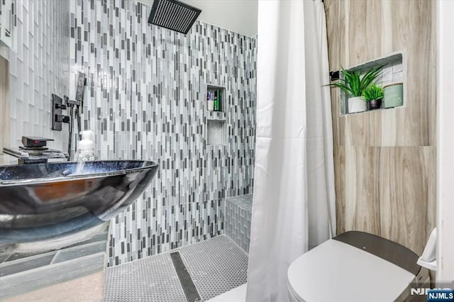 bathroom with a shower with curtain, toilet, and tile walls