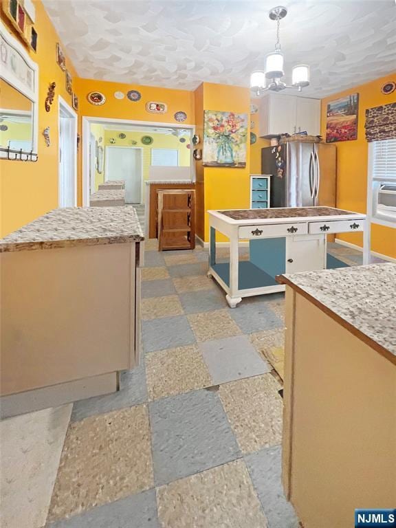 kitchen featuring white cabinetry, hanging light fixtures, stainless steel fridge, and a kitchen island