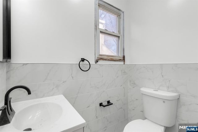 bathroom with vanity, tile walls, and toilet