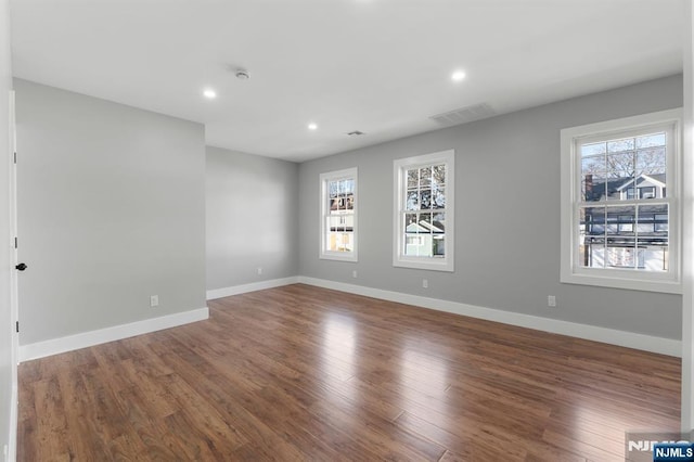 empty room with dark wood-type flooring and a wealth of natural light