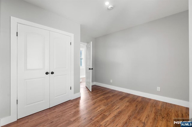 unfurnished bedroom featuring wood-type flooring and a closet