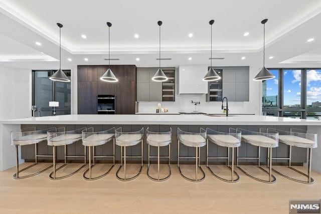 kitchen with a large island, sink, a breakfast bar area, decorative light fixtures, and a raised ceiling