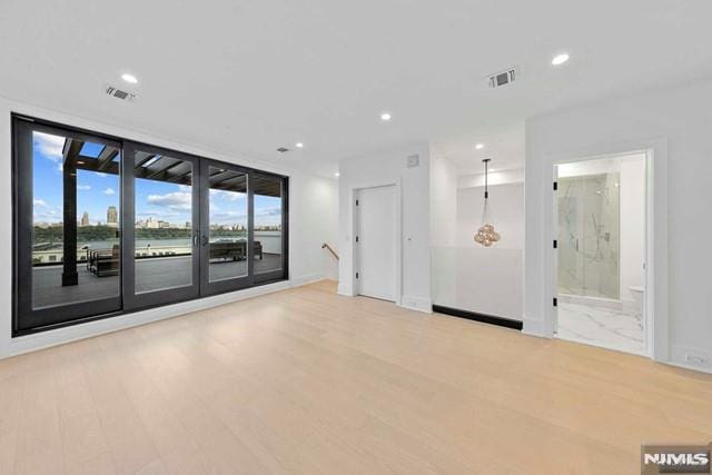 unfurnished room with floor to ceiling windows and light wood-type flooring