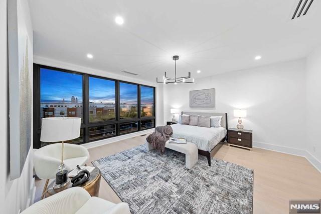 bedroom with an inviting chandelier, light hardwood / wood-style flooring, and a wall of windows