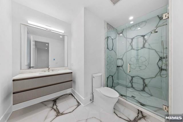 bathroom with vanity, an enclosed shower, and toilet