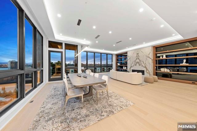 dining space with a raised ceiling, expansive windows, built in features, and light hardwood / wood-style floors