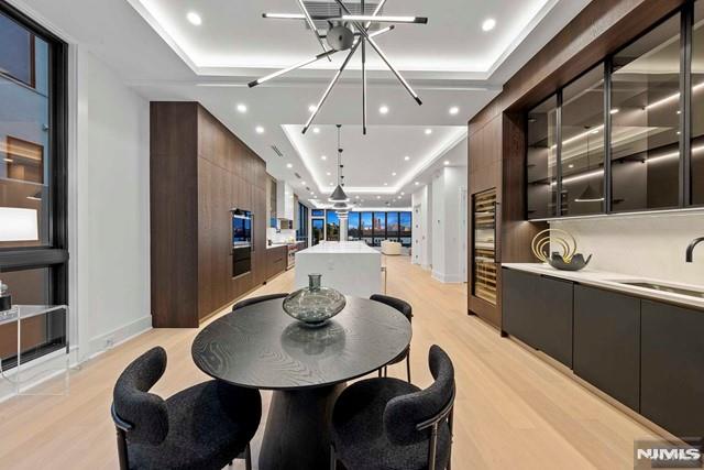 dining space with a tray ceiling, sink, and light wood-type flooring