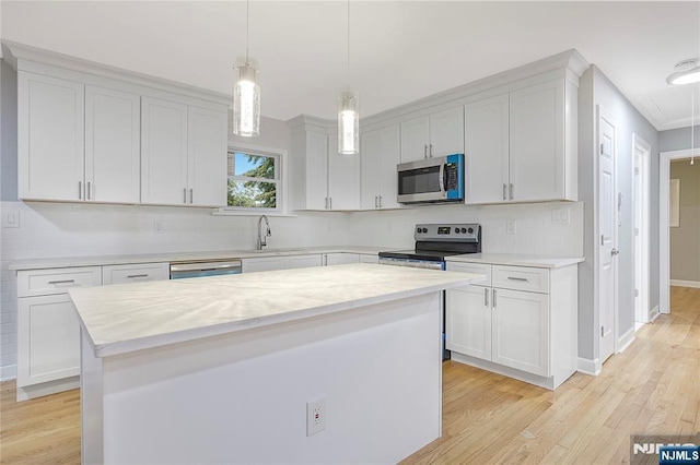 kitchen featuring stainless steel appliances, white cabinetry, a kitchen island, and decorative light fixtures