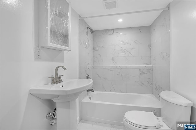 bathroom featuring tiled shower / bath combo and toilet