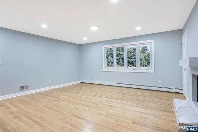 unfurnished living room with a baseboard heating unit, a high end fireplace, and light hardwood / wood-style flooring