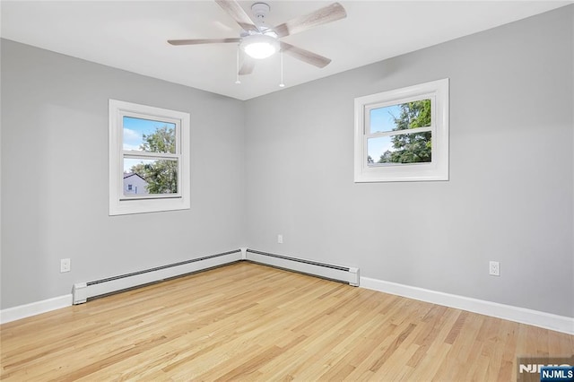 empty room featuring ceiling fan, plenty of natural light, a baseboard heating unit, and light hardwood / wood-style floors