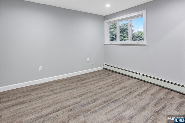 unfurnished room featuring a baseboard radiator and light wood-type flooring