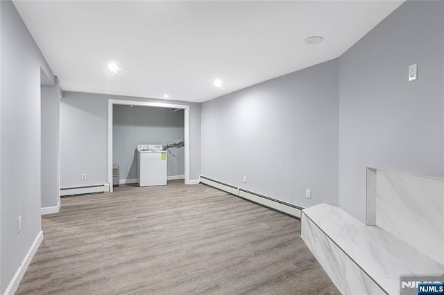 unfurnished bedroom featuring a baseboard radiator, washer / clothes dryer, and light wood-type flooring