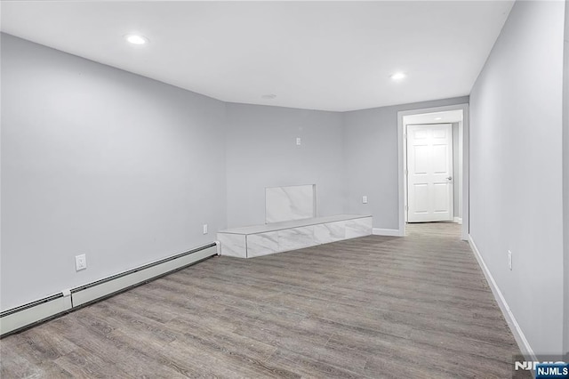 spare room featuring a baseboard radiator and light hardwood / wood-style floors