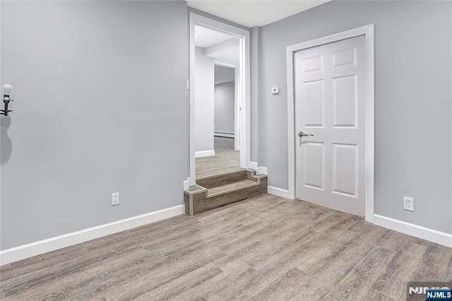 empty room with a baseboard heating unit and light wood-type flooring