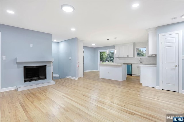 unfurnished living room featuring sink and light hardwood / wood-style floors