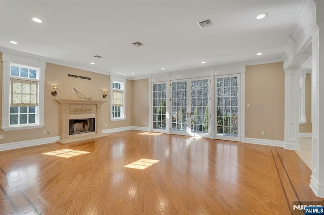 unfurnished living room with crown molding, light hardwood / wood-style floors, and decorative columns