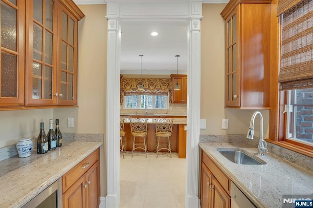 kitchen featuring light stone counters, sink, decorative light fixtures, and wine cooler