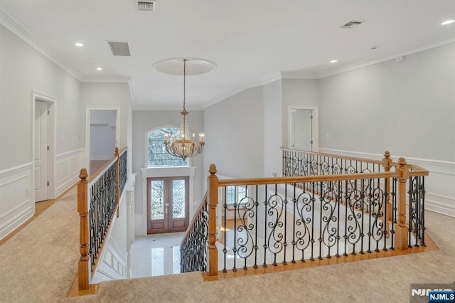 stairway with an inviting chandelier, crown molding, and french doors