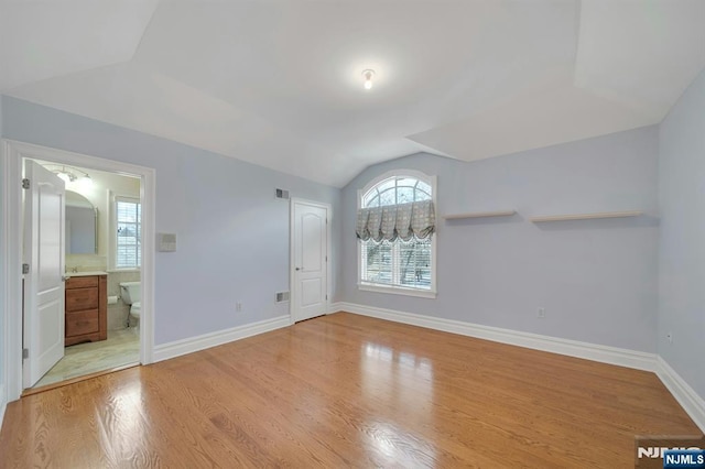 interior space featuring vaulted ceiling, light hardwood / wood-style floors, and ensuite bathroom