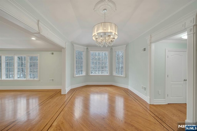 interior space with an inviting chandelier, crown molding, a wealth of natural light, and light wood-type flooring