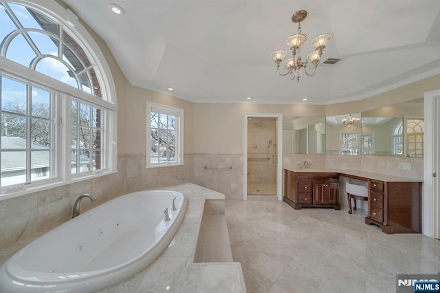 bathroom with tiled tub, vanity, and a chandelier