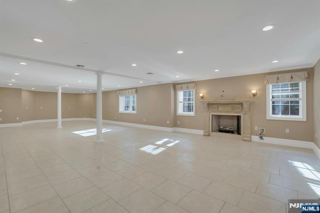 basement with light tile patterned flooring, a high end fireplace, and plenty of natural light