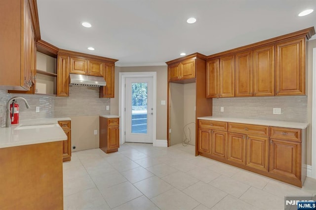 kitchen with tasteful backsplash, crown molding, sink, and light tile patterned floors