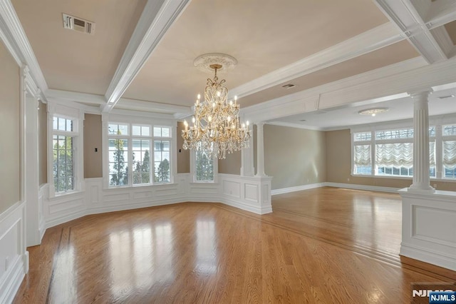 unfurnished dining area with decorative columns, a wealth of natural light, and light wood-type flooring