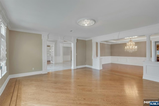 unfurnished room with a notable chandelier, ornamental molding, light hardwood / wood-style floors, and ornate columns