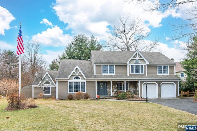 view of front of home featuring aphalt driveway, roof with shingles, an attached garage, covered porch, and a front lawn