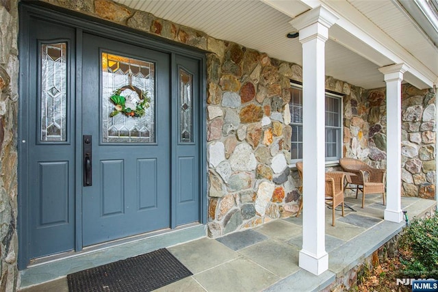 entrance to property featuring stone siding and a porch