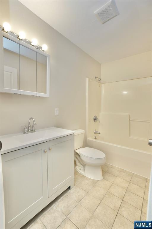 full bathroom featuring vanity, tile patterned floors, toilet, and washtub / shower combination