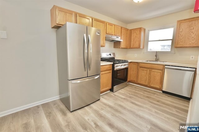 kitchen with stainless steel appliances, sink, and light hardwood / wood-style floors