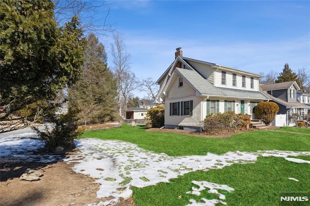 snow covered property featuring a lawn and a chimney