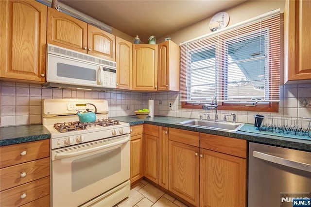 kitchen with tasteful backsplash, sink, white appliances, and light tile patterned floors