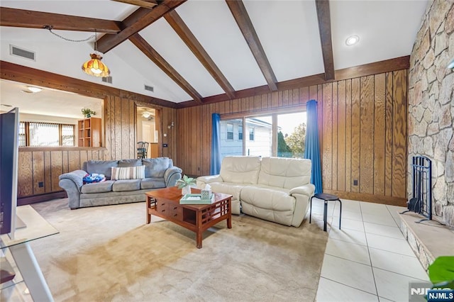 tiled living room with beamed ceiling, wooden walls, high vaulted ceiling, and a stone fireplace