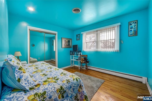 bedroom featuring a baseboard radiator, hardwood / wood-style floors, and a closet