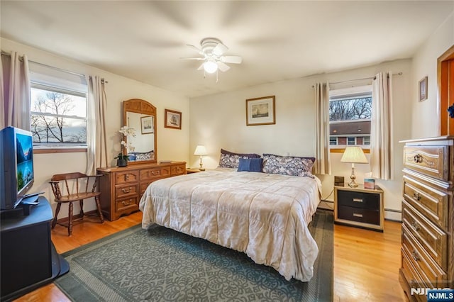 bedroom with wood-type flooring, ceiling fan, and a baseboard radiator