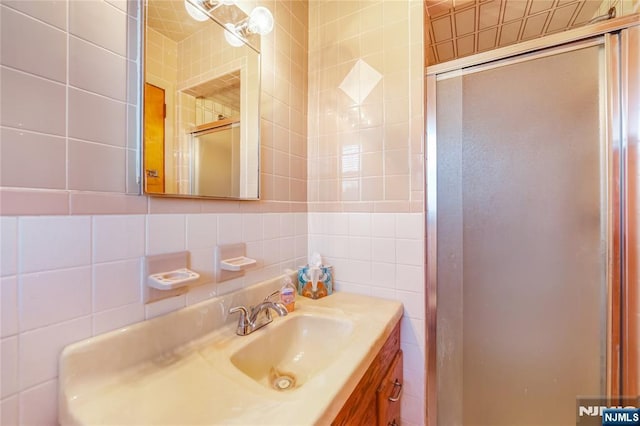 bathroom featuring walk in shower, vanity, tile walls, and backsplash