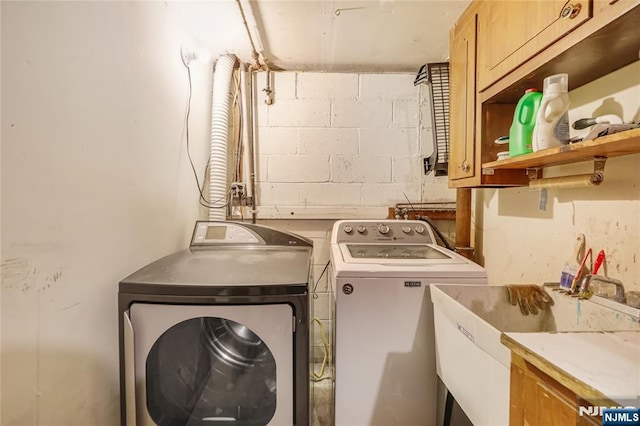 washroom with cabinets, separate washer and dryer, and sink