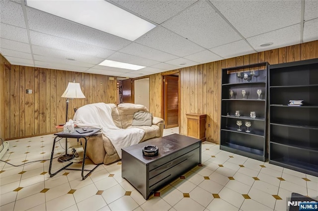 living room with wooden walls and a drop ceiling