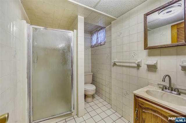 bathroom with tile patterned flooring, vanity, a shower with door, and tile walls