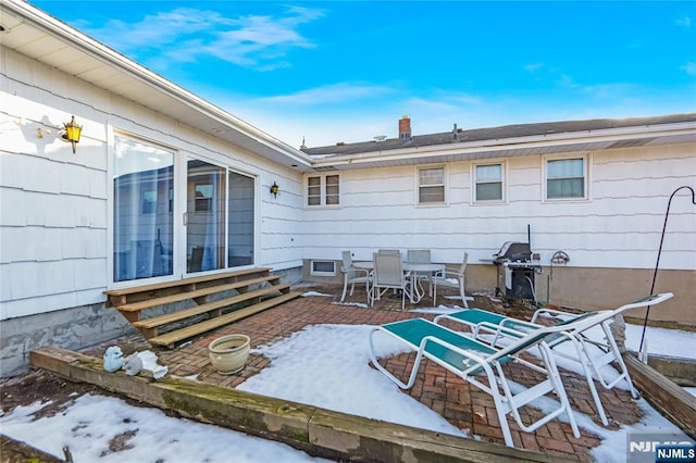 snow covered patio with a grill